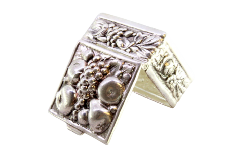 Caixa de comprimidos em prata com relevos de frutos revelados na tampa com tampa basculante